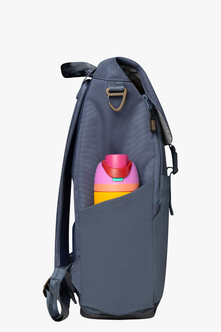 Side view of blue backpack showing stretchy bottle pocket on side of backpack, holding bright yellow and pink water bottle.