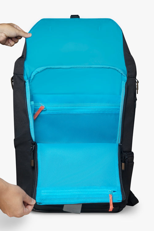 Front view of hands holding an opened black backpack against white background. Image shows blue interior of backpack and orange zipper pull.