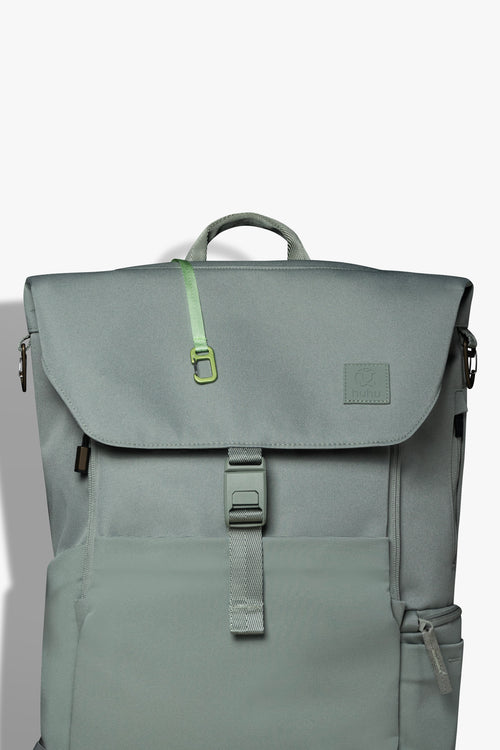 Front view of green backpack against white background. Green key hook is hanging out from the zipper pocket on top of the backpack.