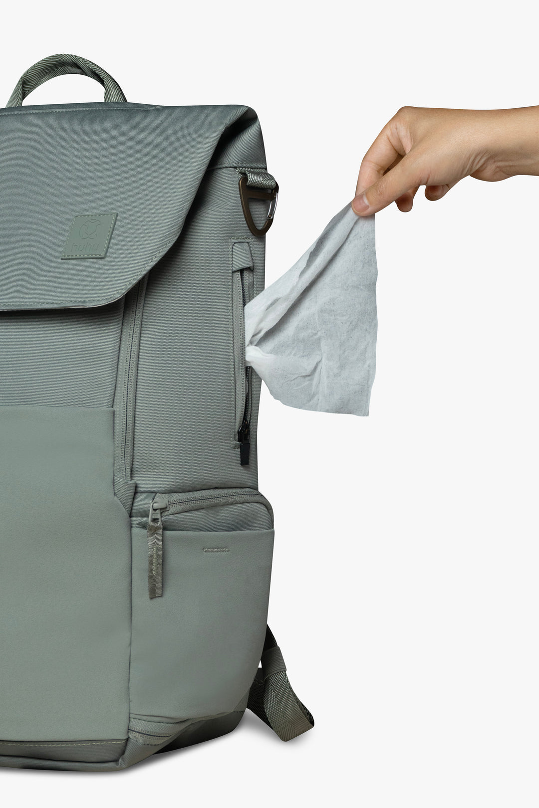 Front view of green backpack with hand pulling wipe from exterior wipes pocket on side of backpack.