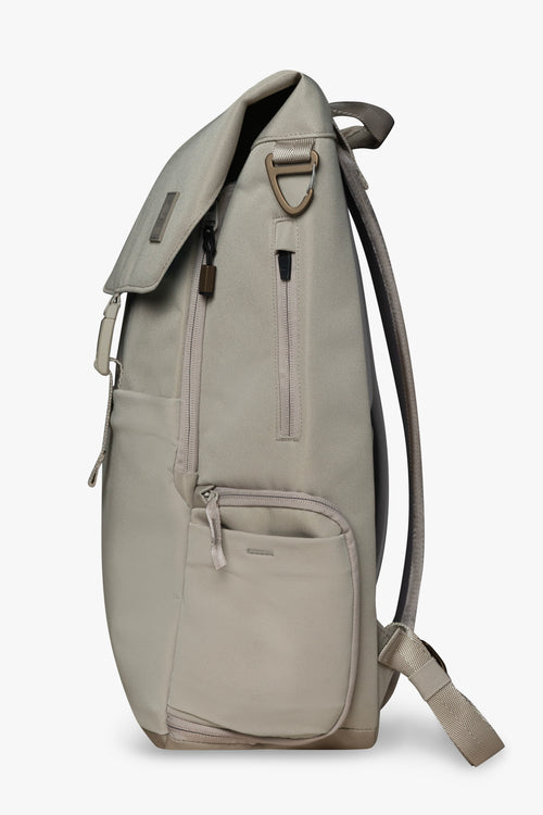 Side view of taupe backpack showing zipper pockets and bronze carabiner clip against a white background.