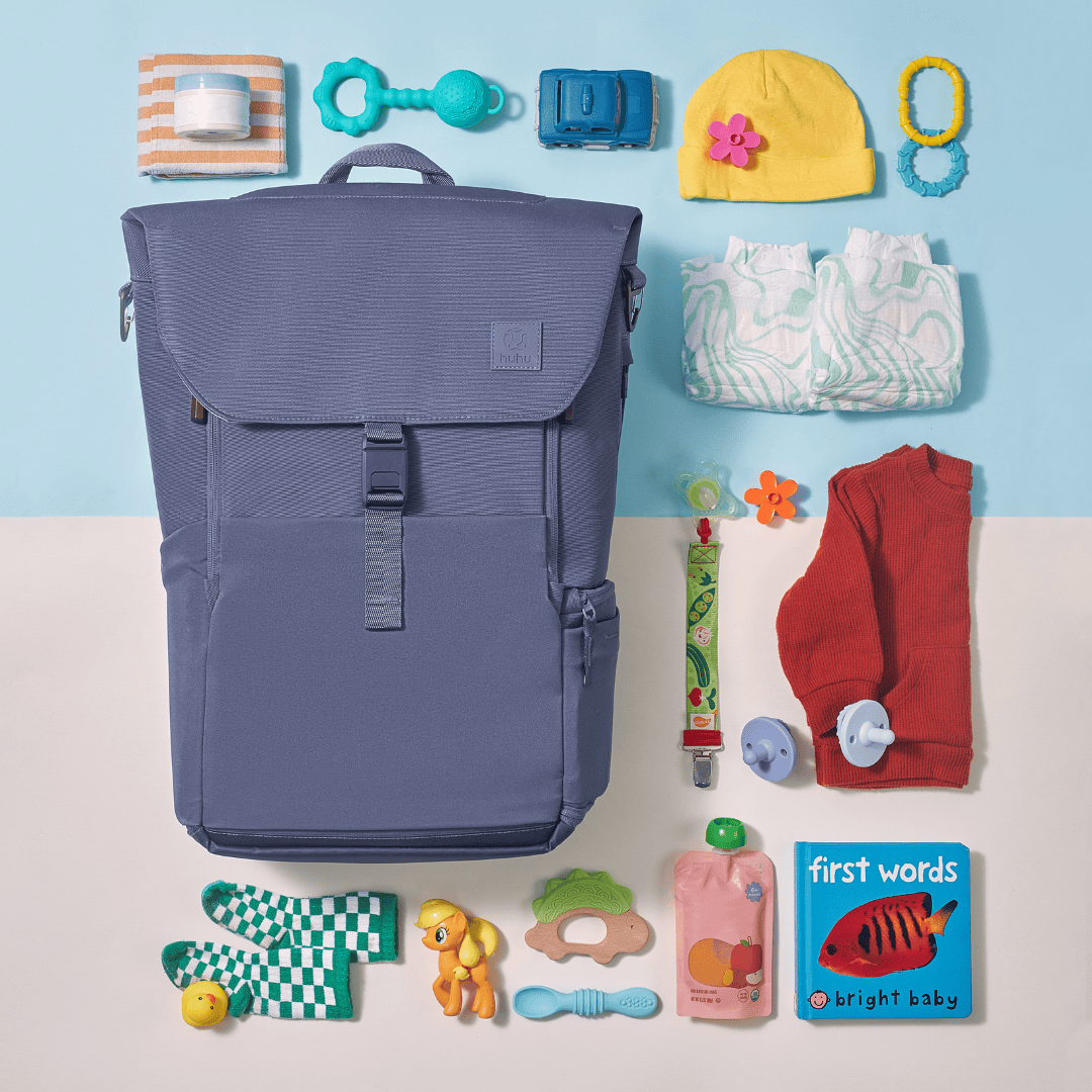 Flat lay of blue backpack and brightly colored children's items against a beige and blue background. Purpose is to show contents that can be packed into backpack.