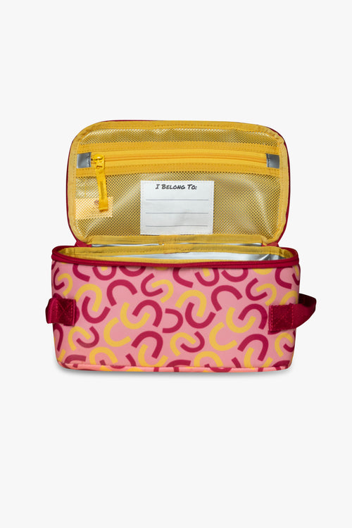 Front view of open pink and yellow macaroni patterned insulated cooler bag to reveal yellow mesh zippered pocket and white "I belong to" tag against a white background.
