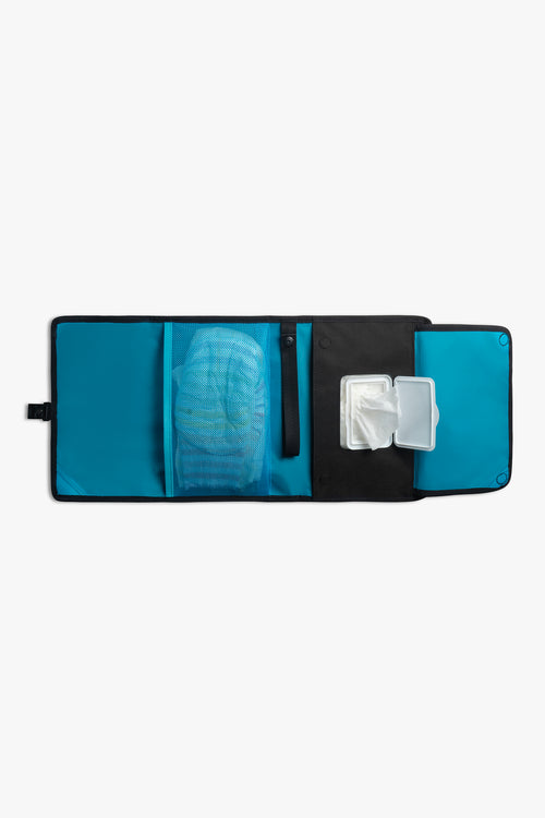 Front view of horizontal opened black changing wallet with blue interior against a white background. Shows diapers in a blue mesh pocket, a black strap, and wipes in a designated wipes pocket.