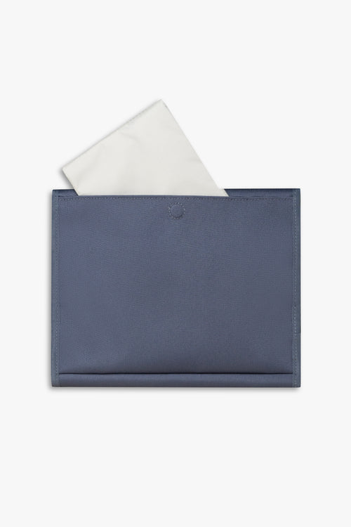 Back view of closed blue changing wallet against a white background showing taupe changing pad sitting halfway out of back pocket.