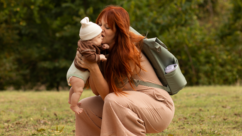 mom wearing backpack holding baby
