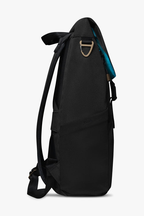 Side view of black backpack showing stretchy bottle pocket, padded strap, and bronze carabiner clip against a white background. Blue interior of bag shows on top flap of backpack.