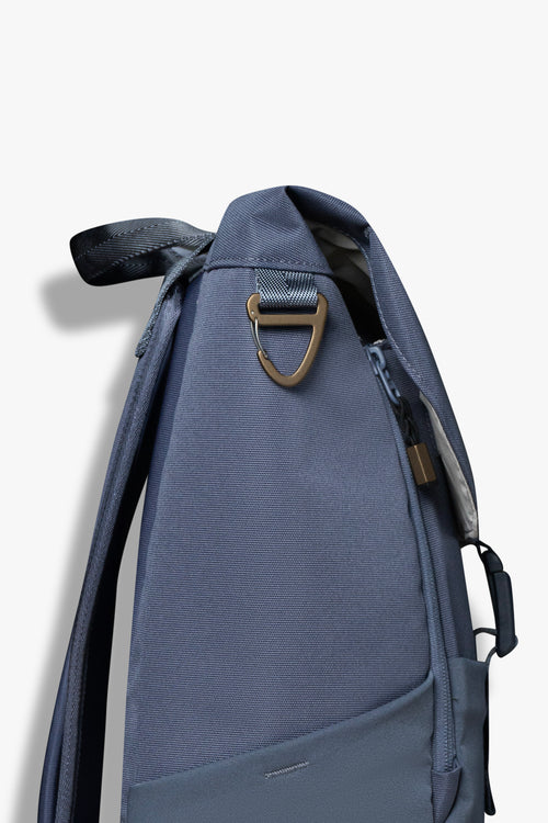 Side view of blue backpack showing bronze carabiner clip hook.