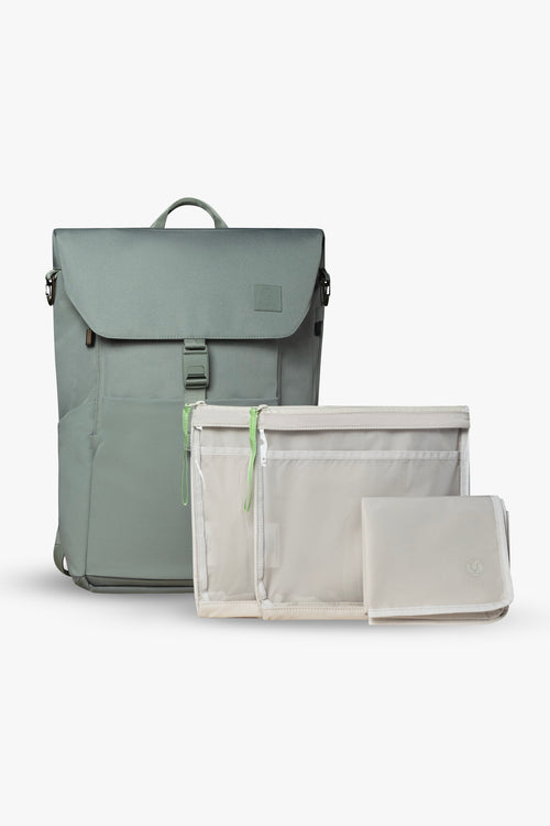Front view of green backpack, closed and standing upright with 2 taupe packing pouches and 1 blue folded changing pad against white background.