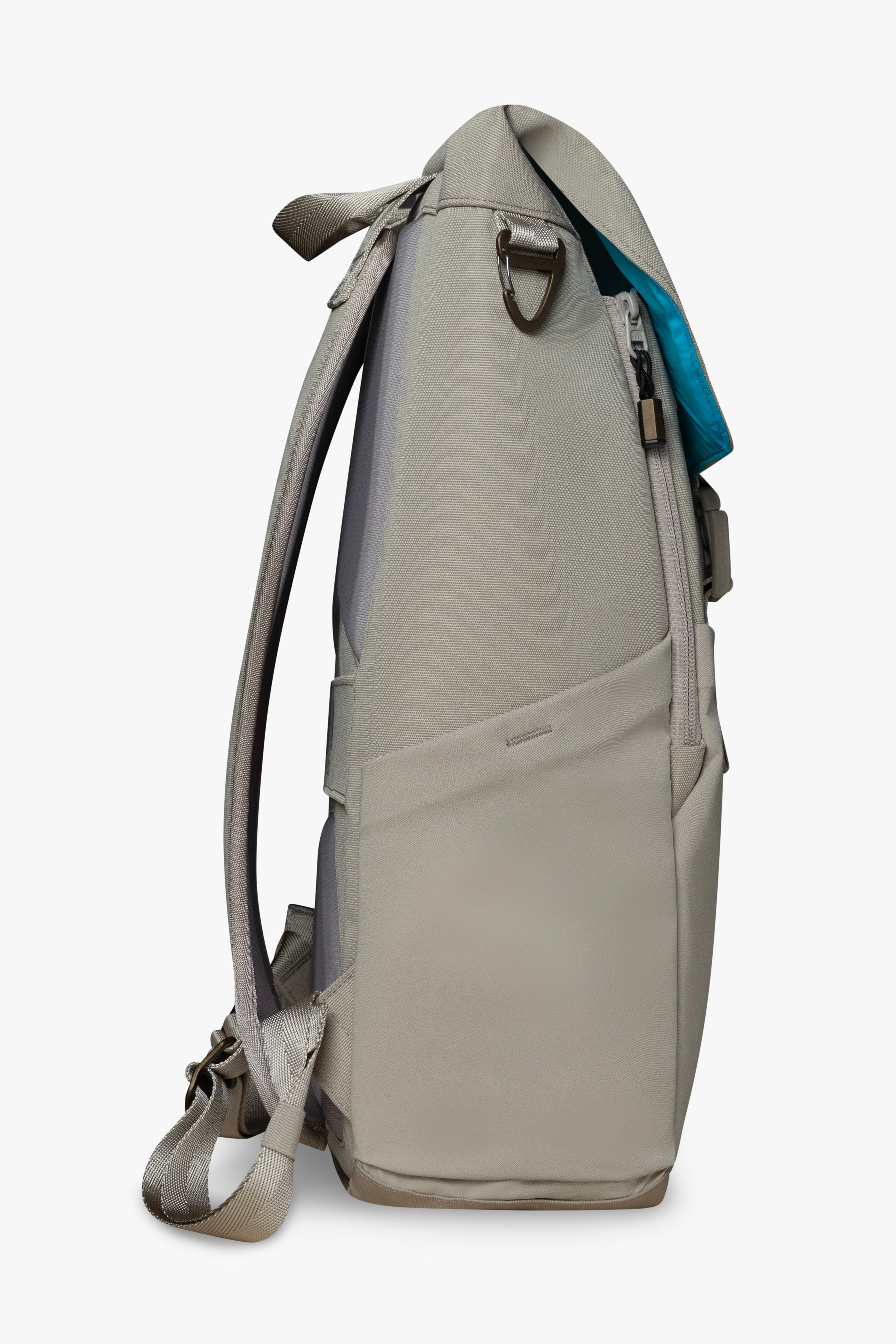 Side view of taupe backpack showing stretchy bottle pocket, padded strap, and bronze carabiner clip against a white background. Blue interior of bag shows on top flap of backpack.