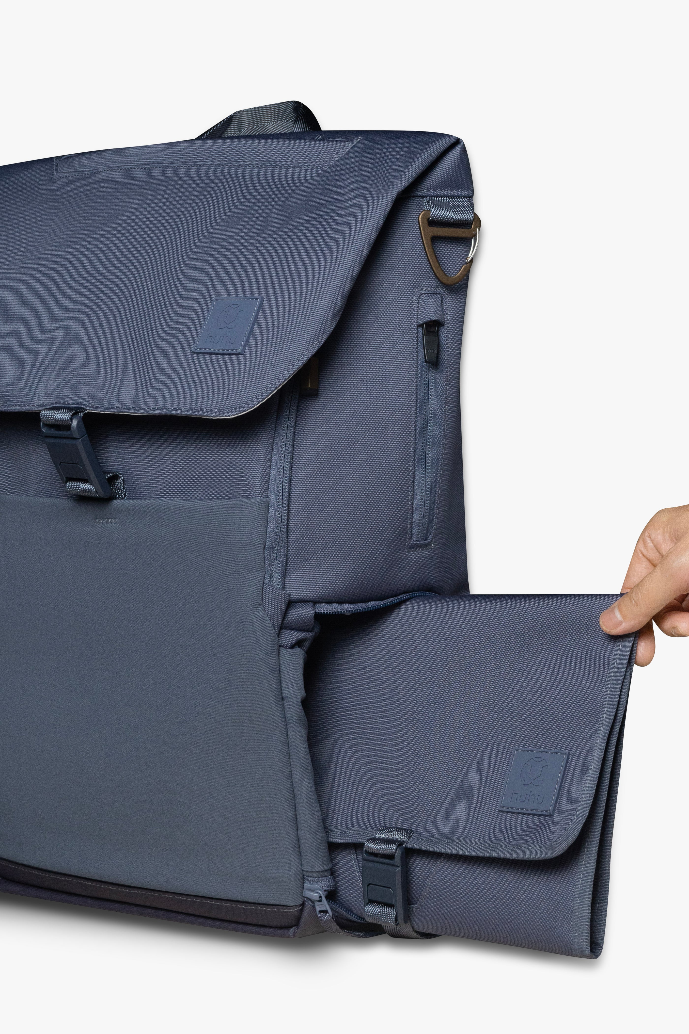 Hand sliding blue changing wallet into side locker pocket of blue backpack against white background.