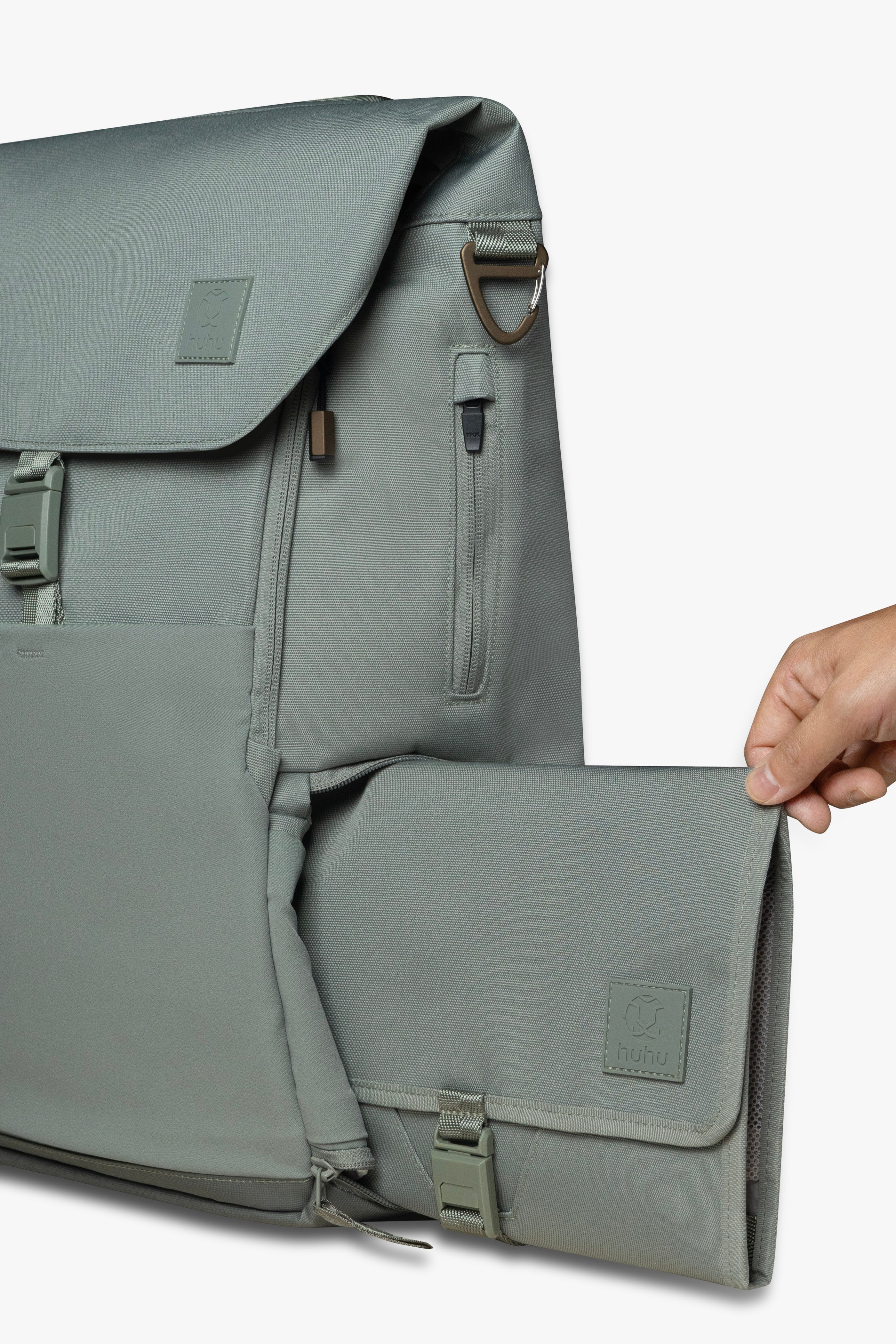 Hand sliding green changing wallet into side locker pocket of green backpack against white background.