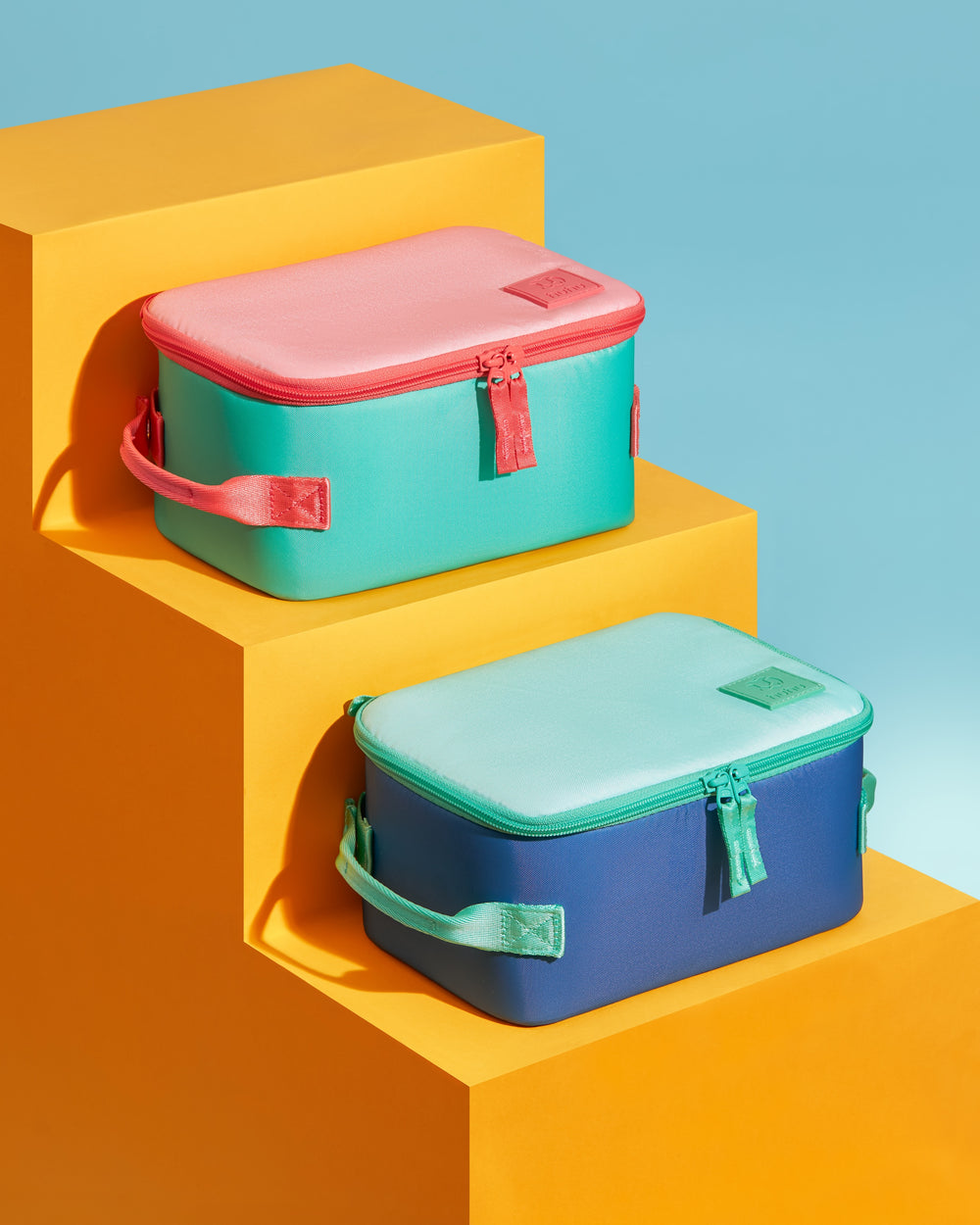Two colorful lunch boxes on a geometric background