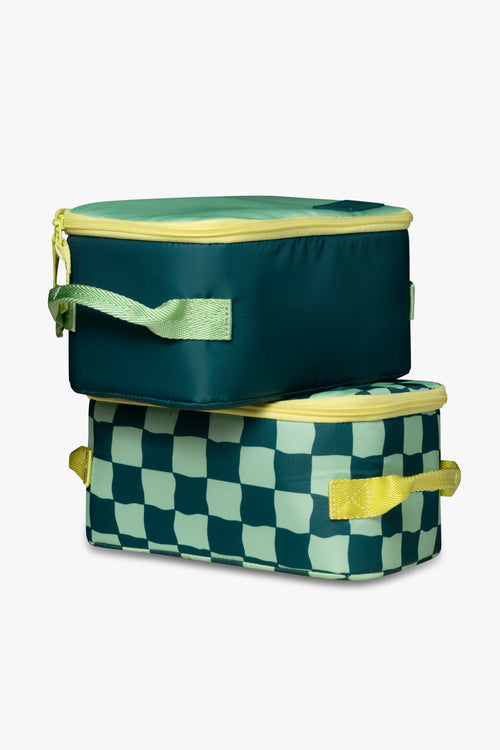 Solid green insulated cooler bag with yellow zipper sitting on top of green checkered insulated cooler bag with yellow zipper against a white background.