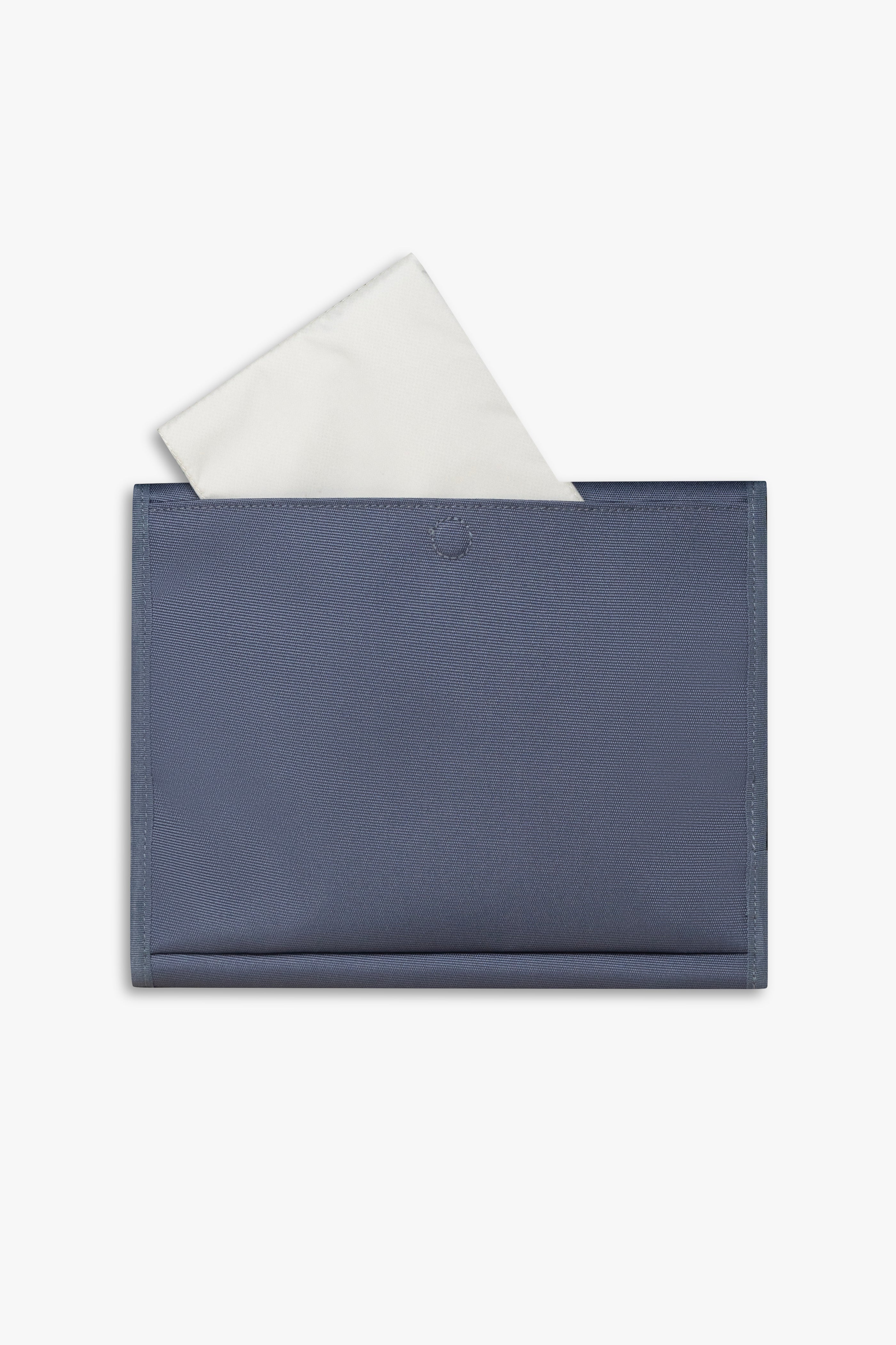 Back view of closed blue changing wallet against a white background showing taupe changing pad sitting halfway out of back pocket.