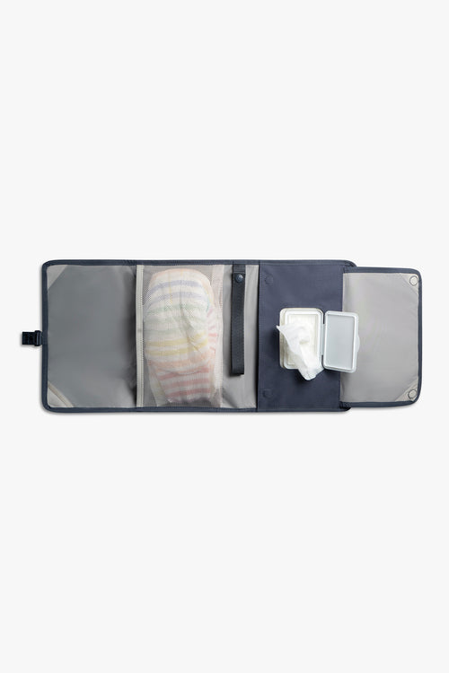 Front view of horizontal opened blue changing wallet with taupe interior against a white background. Shows diapers in a taupe mesh pocket, a blue strap, and wipes in a designated wipes pocket.