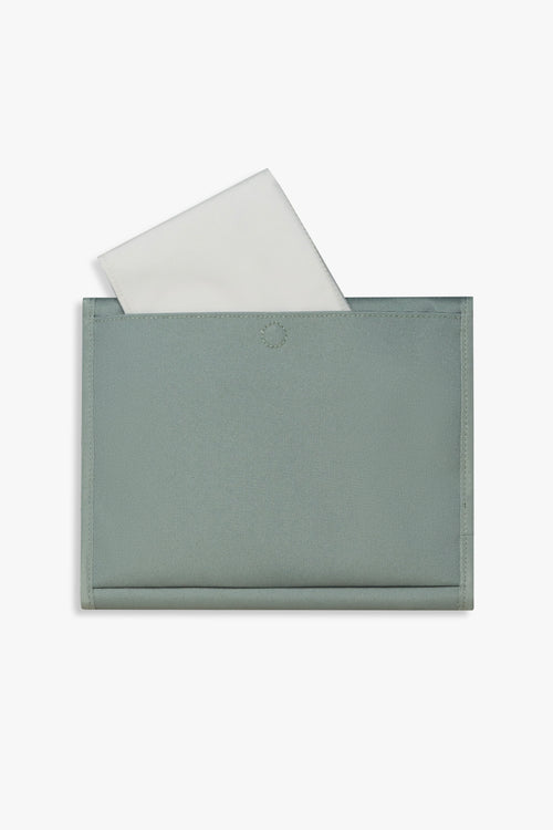 Back view of closed green changing wallet against a white background showing taupe changing pad sitting halfway out of back pocket.