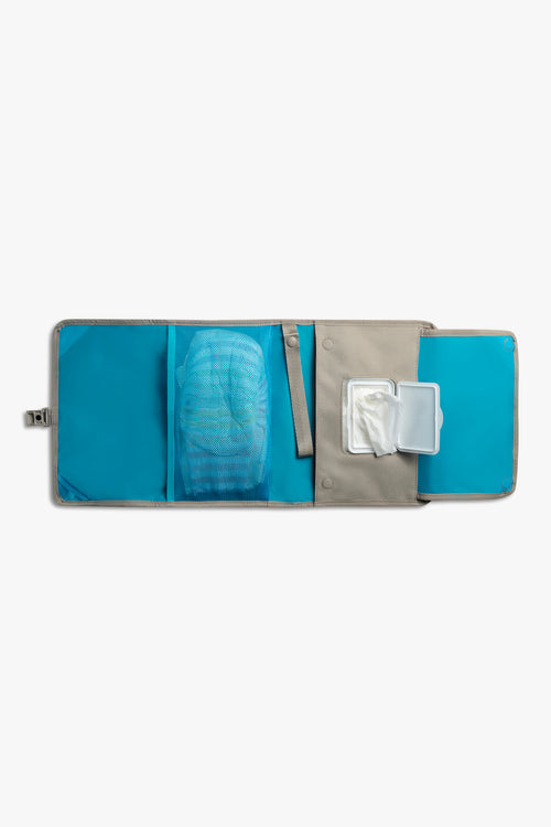 Front view of horizontal opened taupe changing wallet with blue interior against a white background. Shows diapers in a blue mesh pocket, a taupe strap, and wipes in a designated wiped pocket.